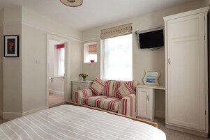 A bedroom with a bed, a sofa, a television, and a wardrobe.