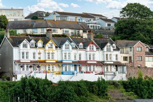 A row of colorful terraced houses with a stone wall in the foreground.