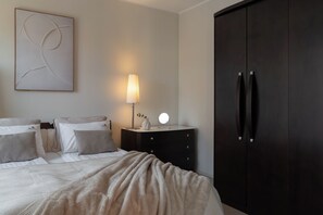 A hotel room with a bed, bedside table, lamp, mirror, and wardrobe. - Szafarnia in Old Town with parking (Gdańsk)