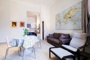 Een moderne woonkamer met een eethoek, een bank, een fauteuil en een grote wereldkaart aan de muur.