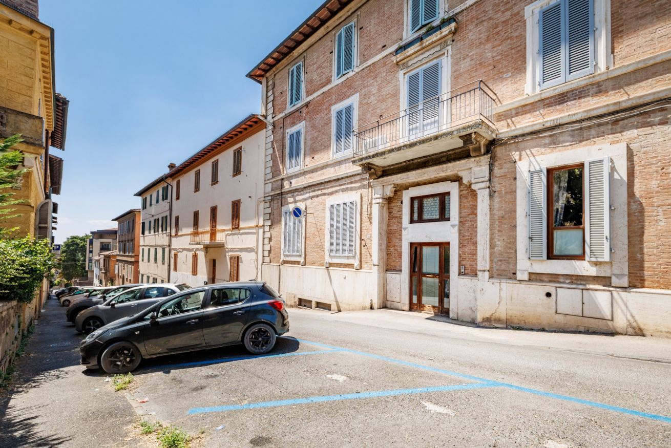 A street with parked cars and buildings with balconies.
