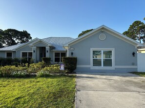 A residential building with a grey exterior, a front entrance, and a visible address sign.