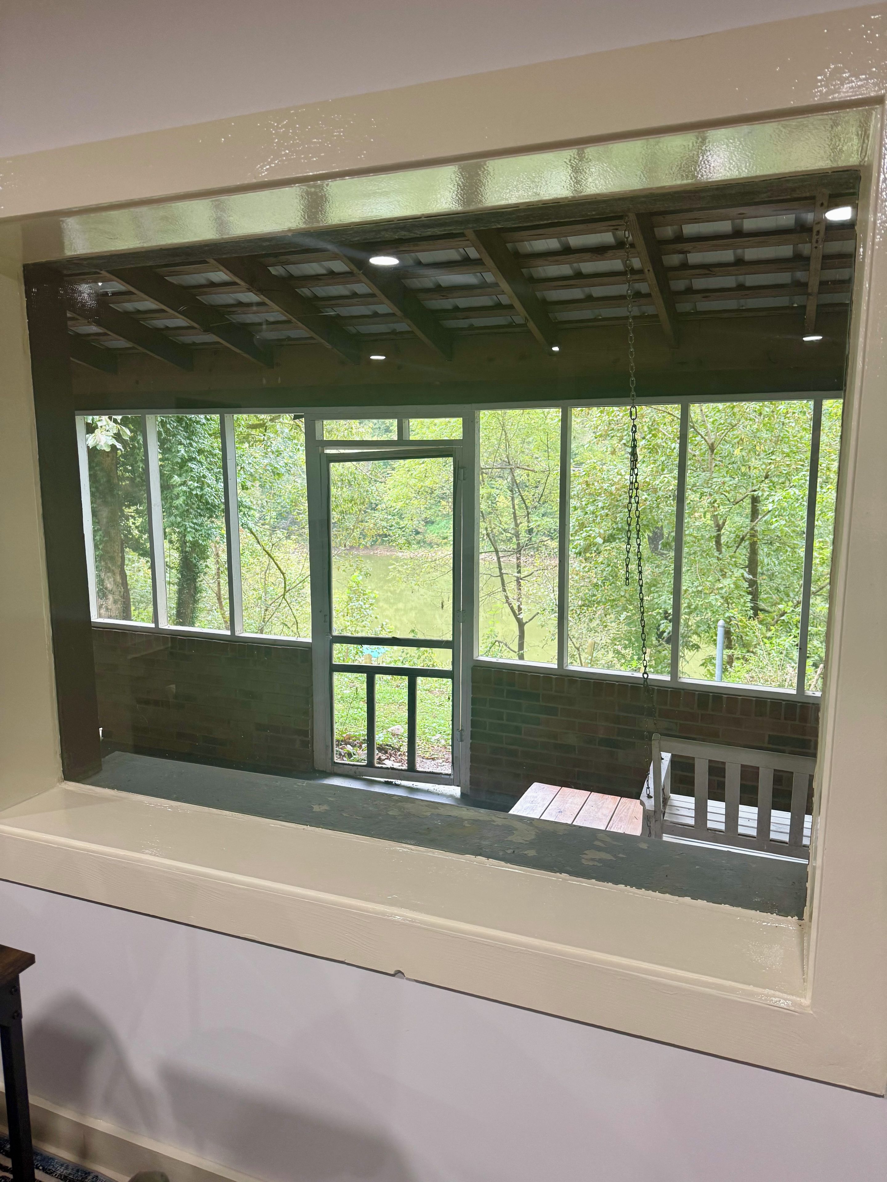 A window with a view of a wooden deck and a brick wall.