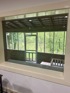 Une fenêtre donnant sur une terrasse en bois et un mur de briques.