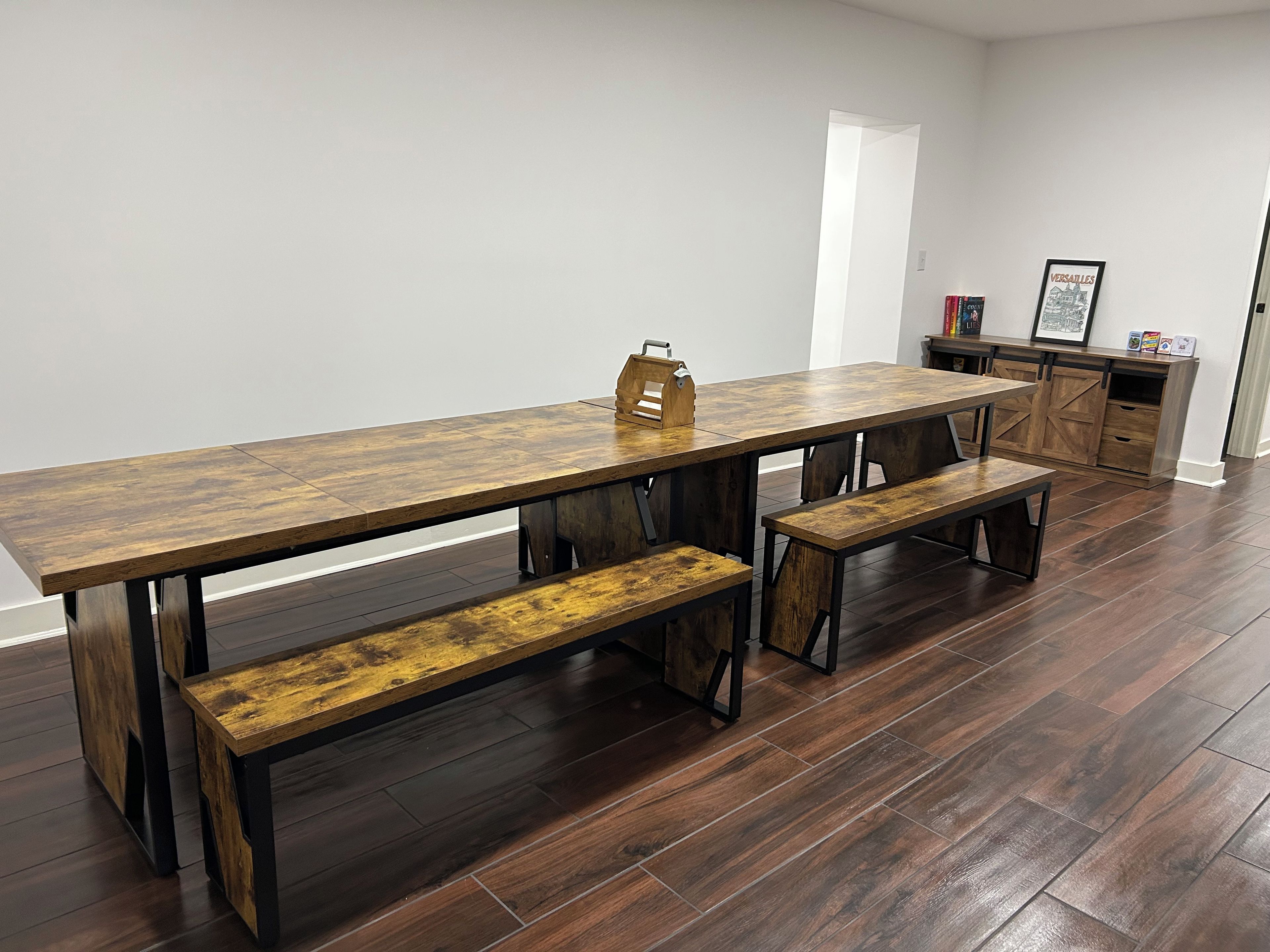 Un espace repas comprenant une longue table en bois, des bancs et un buffet.