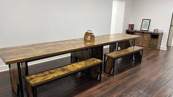 Un espace repas comprenant une longue table en bois, des bancs et un buffet.