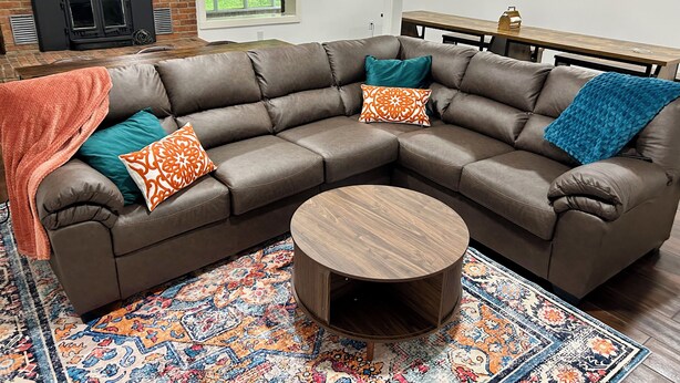A modern living room with a sectional sofa, a round coffee table, and a patterned rug.