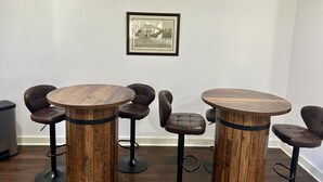 Ein Zimmer mit zwei runden Holztischen und sechs Ledersesseln.