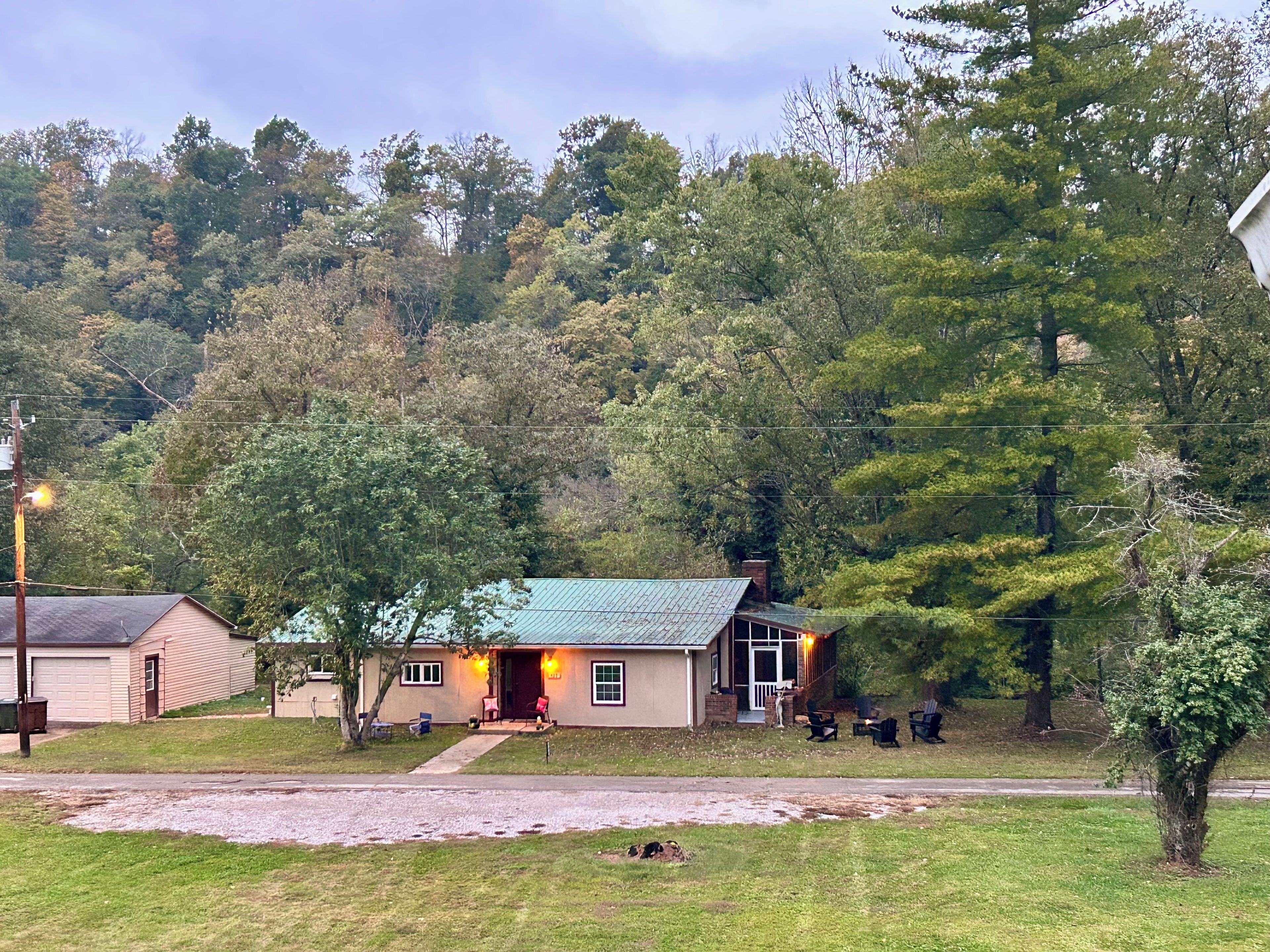 A residential house with a green roof, a front porch with seating, and a driveway.