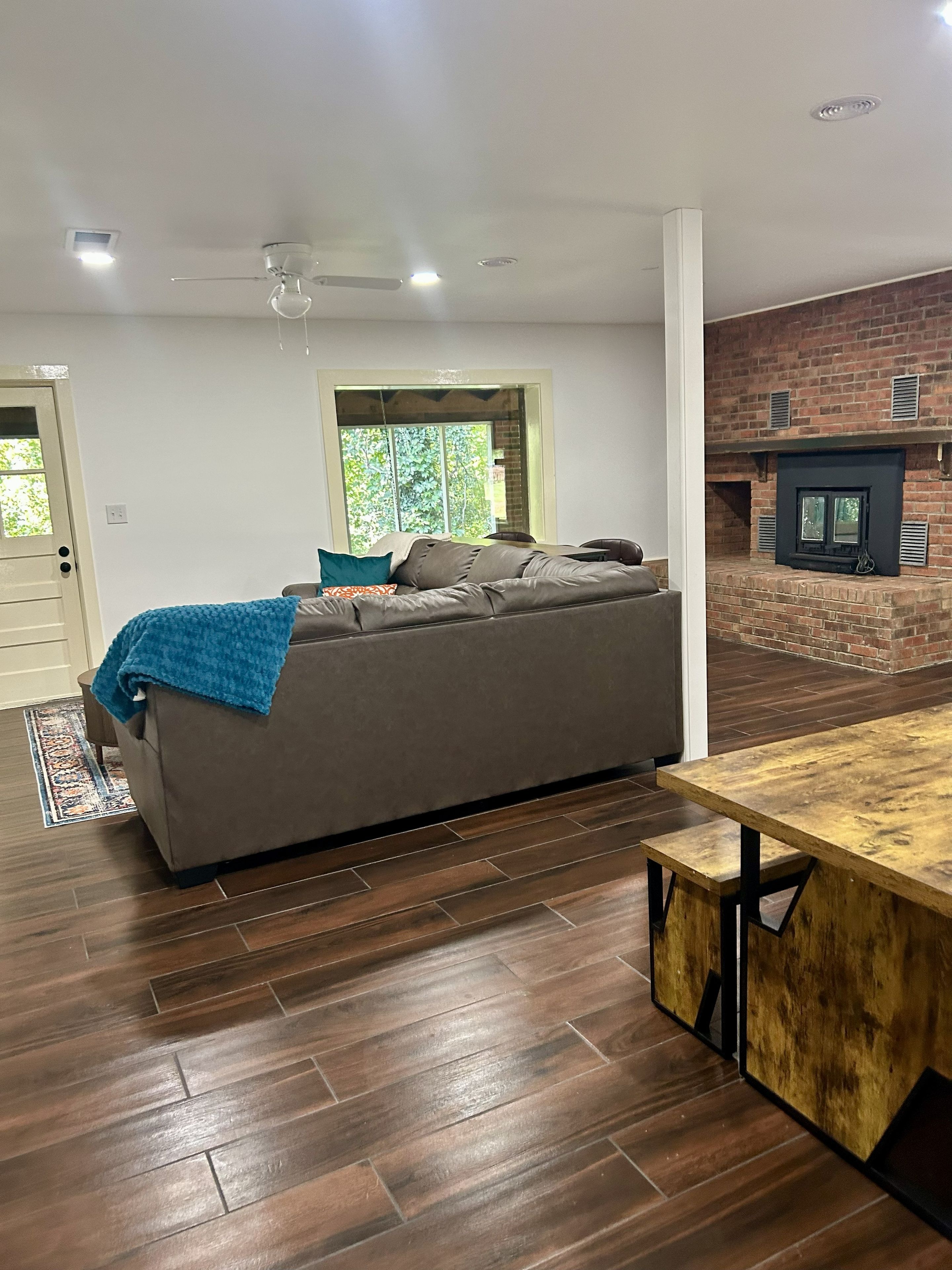 A modern living room with a sofa, a wooden table, and a brick fireplace.