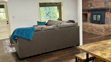 A modern living room with a sofa, a wooden table, and a brick fireplace.