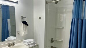 Ein modernes Badezimmer mit einem weißen Waschtisch, einer Duschkabine und einer Toilette.