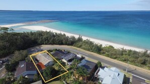 Vista aérea de una propiedad costera con playa, carretera y área delimitada para construcción.