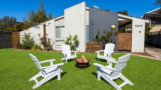 Una casa moderna con césped cuidado y zona de estar al aire libre.