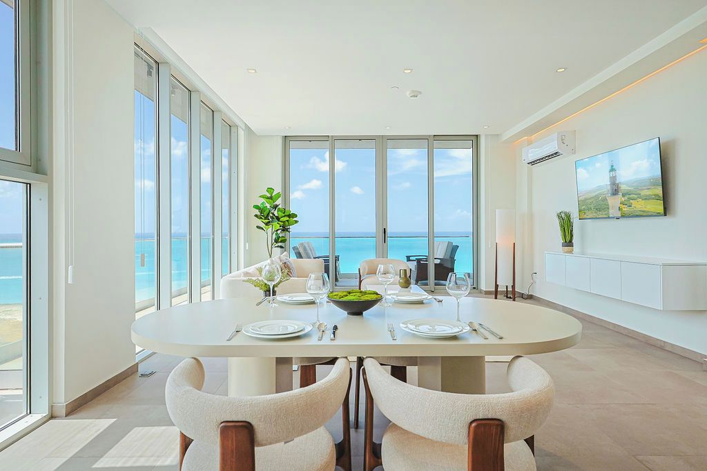 A dining area with a large table, chairs, and a view of the ocean.