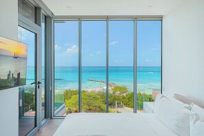 Ein Schlafzimmer mit einer großen Schiebeglasdoor, die auf einen Balkon mit Meerblick führt.