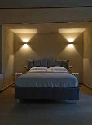Une chambre moderne avec un grand lit, deux tables de chevet et des lampes fixées au mur.