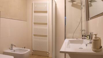 Un baño moderno con ducha de vidrio, lavamanos blanco con espejo y un bidé.