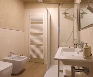 Une salle de bain moderne avec une douche à parois de verre, un lavabo blanc avec un miroir et un bidet.