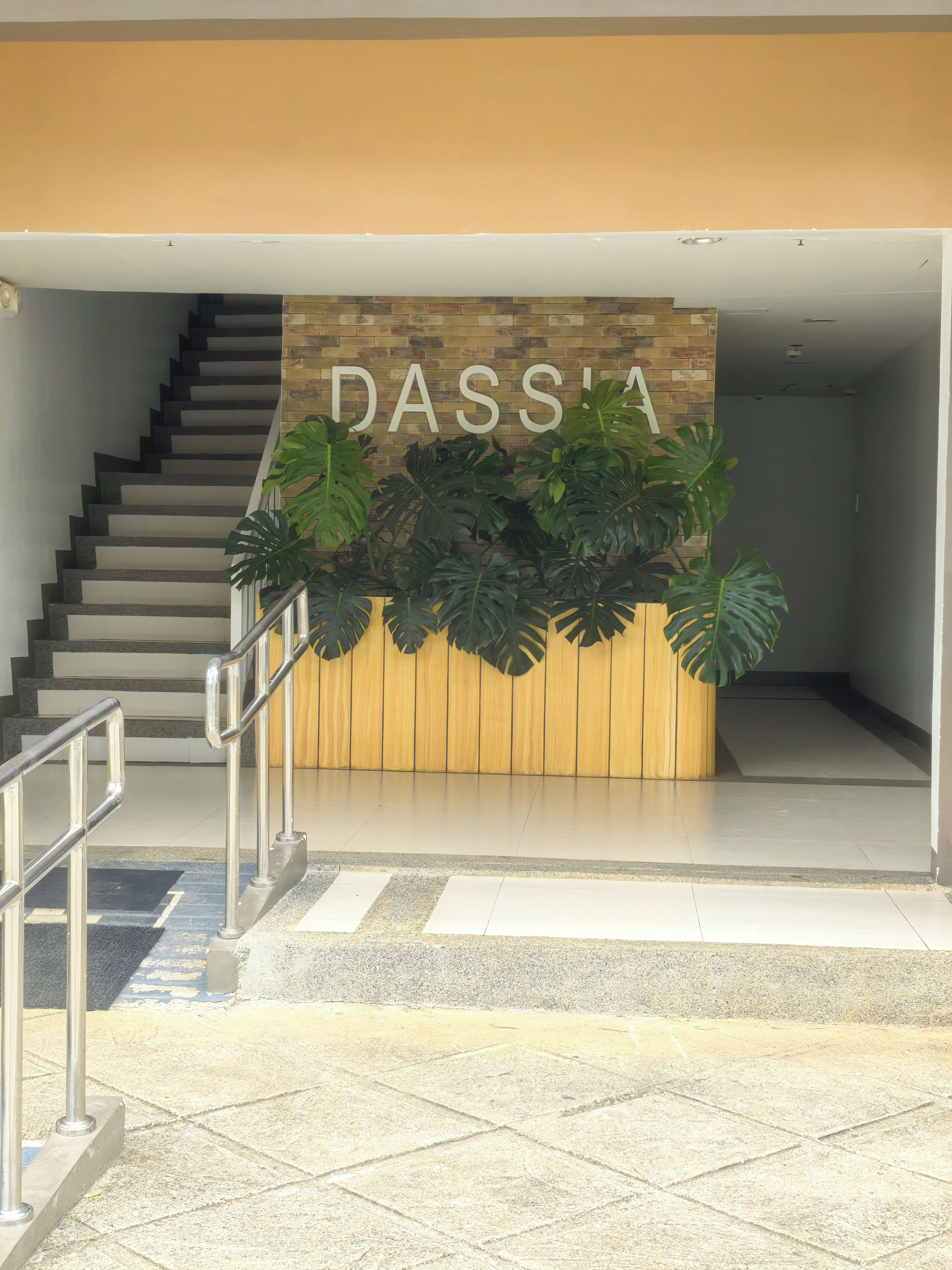 A staircase leading to a reception area with a wooden panel and the word 'DASSIA' on it.