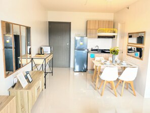 A modern kitchen with a dining area, stainless steel appliances, and wooden cabinetry. - Island Bliss Studio, Balcony, Pool, Gym and Near Airport (PUERTO PRINSESA)