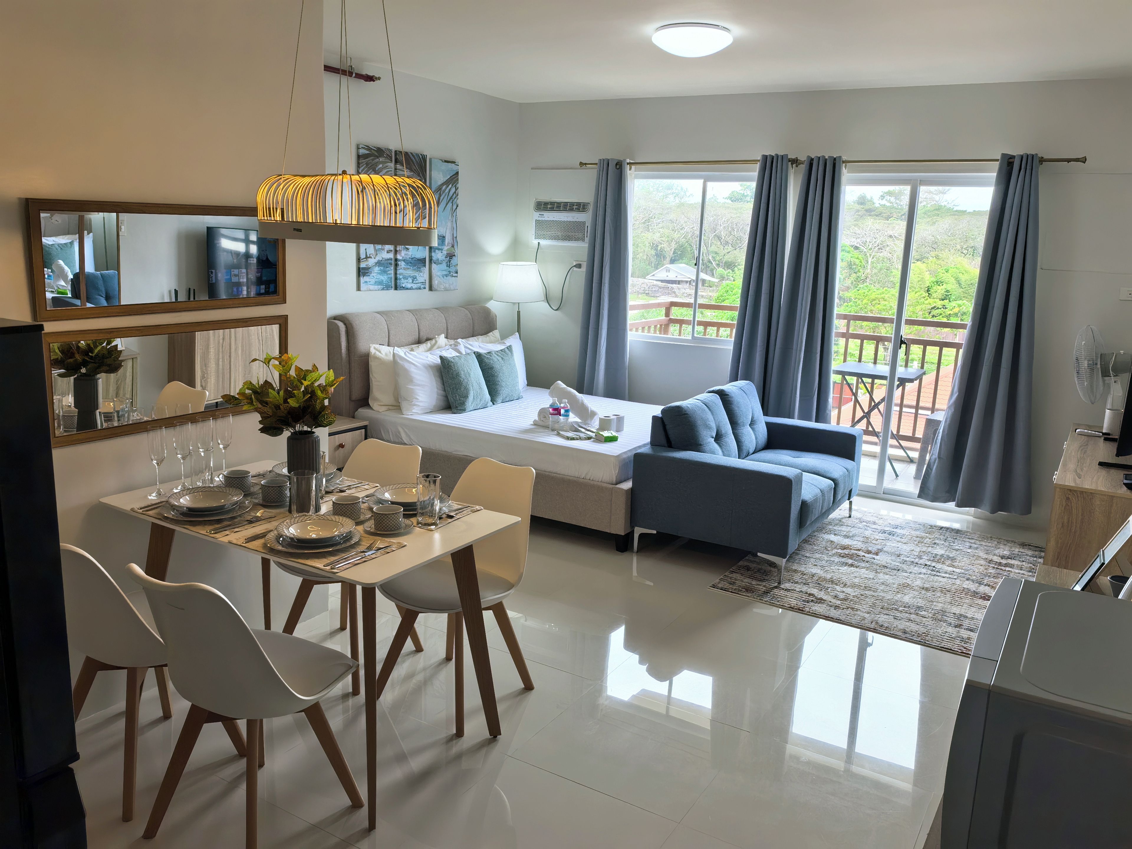 En moderne stue med sofa, spisebord og et stort vindue med gardiner.