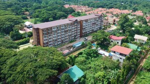 Hotel a più piani con un cortile centrale, circondato da vegetazione lussureggiante e uno sfondo montuoso.