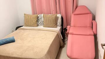 Un dormitorio con una cama, una silla rosa y cortinas rosas.