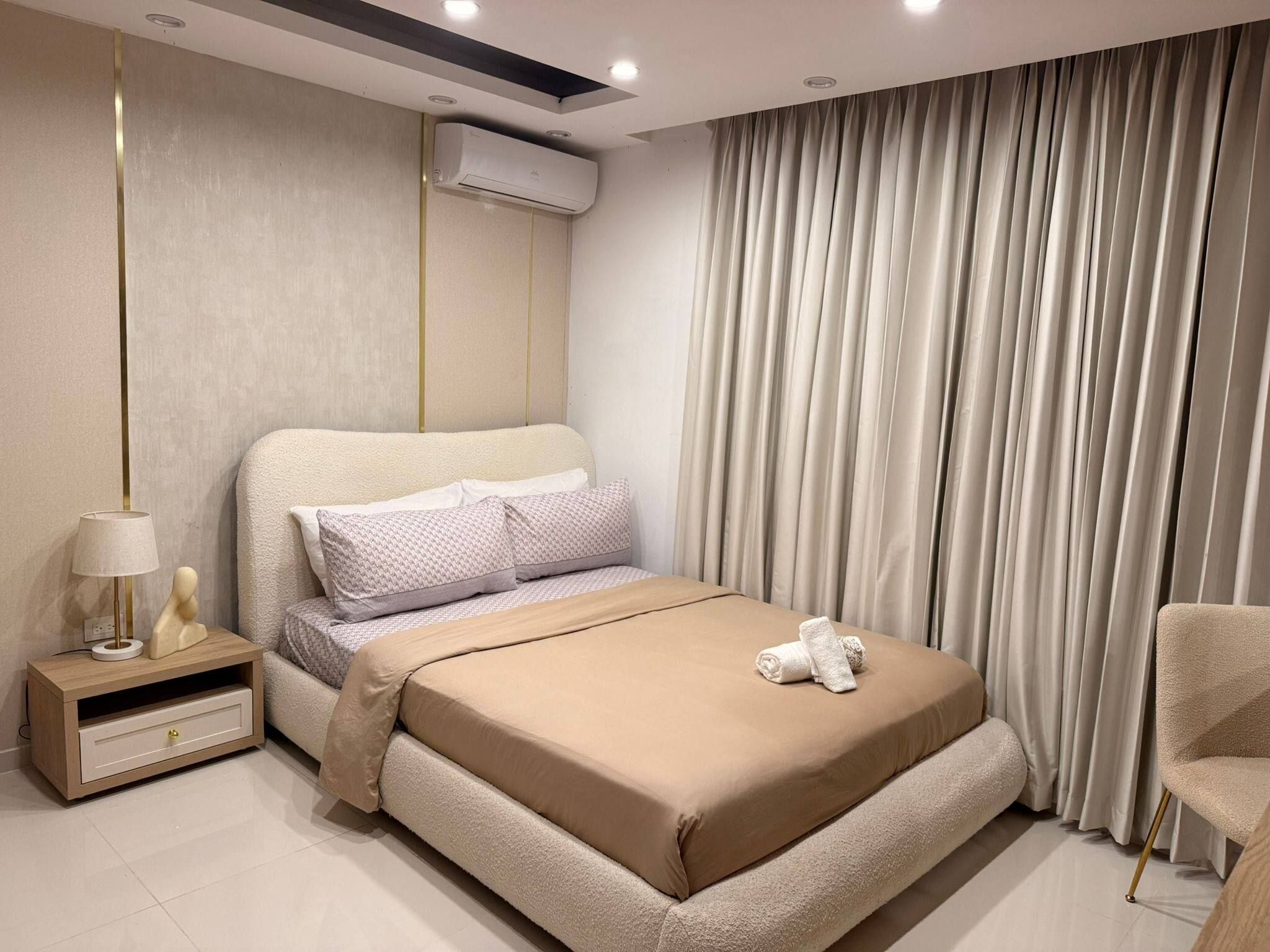 Un dormitorio moderno con una cama, una mesita de noche, una lámpara y una silla.