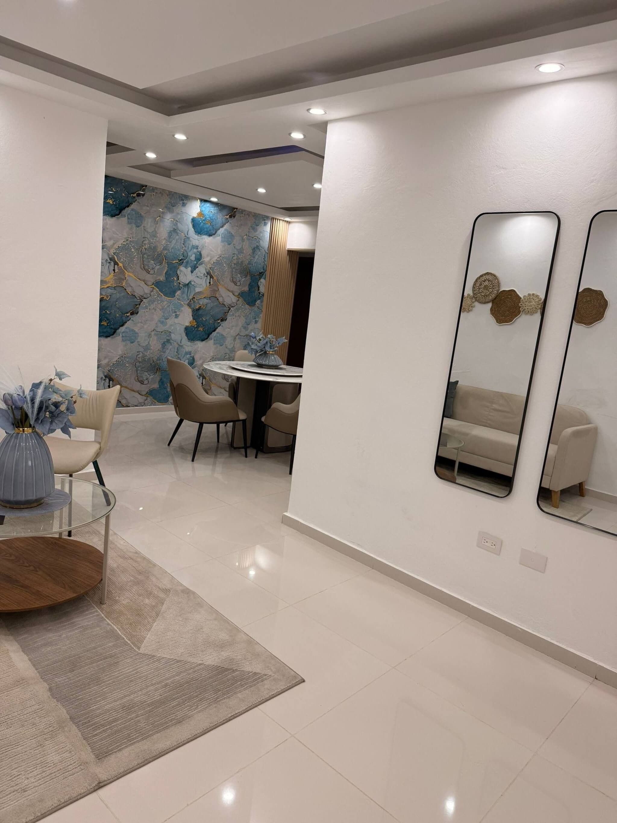 Un comedor moderno con una mesa redonda, sillas y un jarrón decorativo.