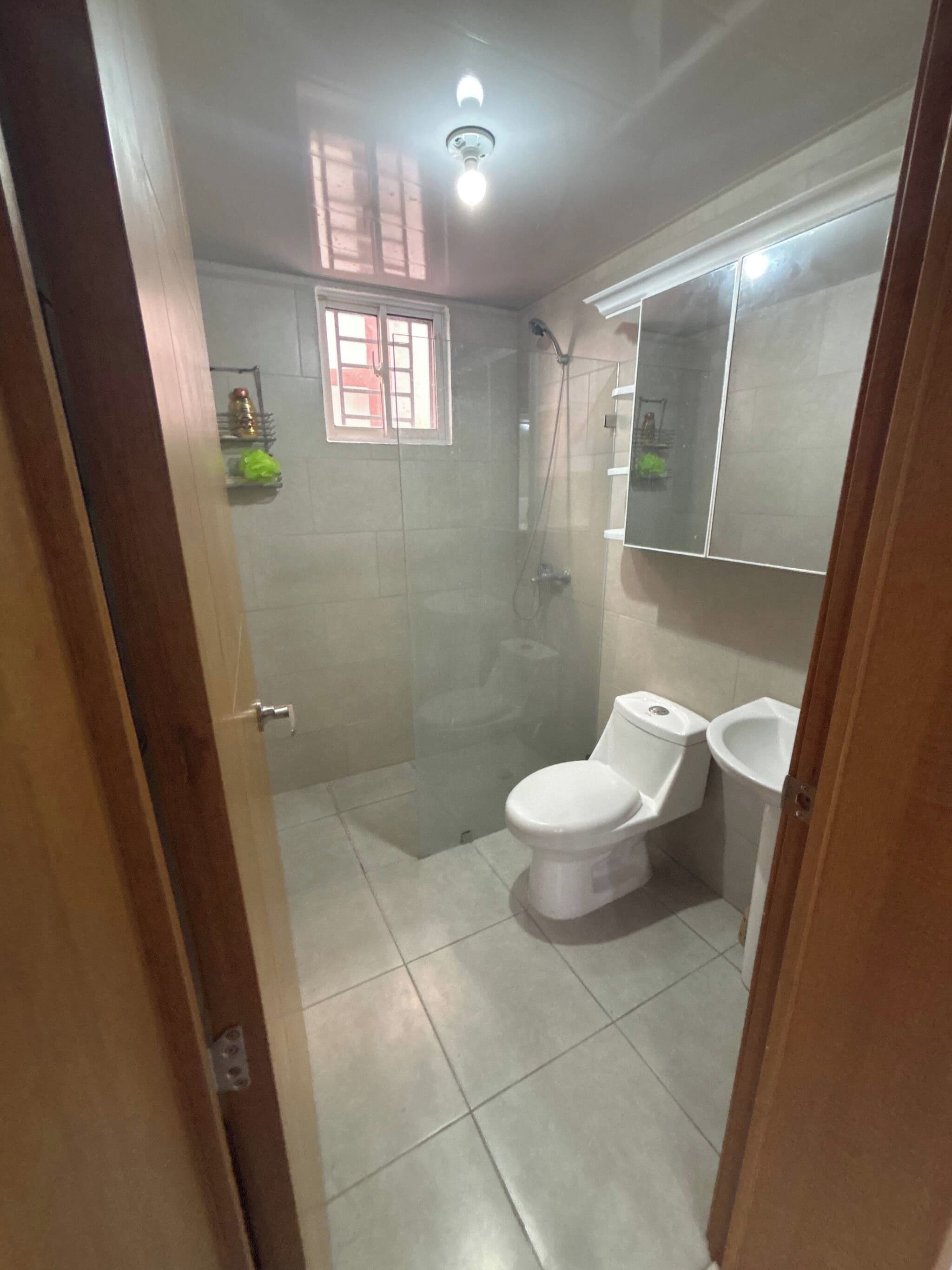Un baño con ducha de vidrio, inodoro y lavamanos.