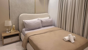 A modern hotel room with a bed, a nightstand, a lamp, and an air conditioning unit. - Nice Apartment Close to Everything (Santo Domingo Norte)