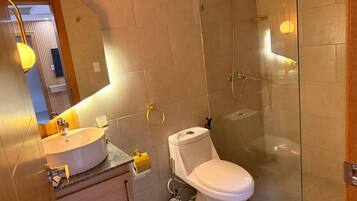 Un baño moderno con cabina de ducha de vidrio, inodoro blanco y tocador con lavamanos.