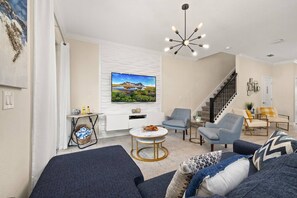 Ein modernes Wohnzimmer mit Flachbildfernseher, einer Treppe und einem Essbereich.