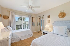 A hotel room with two beds, a ceiling fan, a balcony with a view, and a large mirror. - The Shell House • Ocean Front • Beach Access •Pool (St. Augustine)