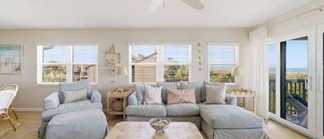 A spacious living room with a large sectional sofa, a wooden coffee table, and a ceiling fan.