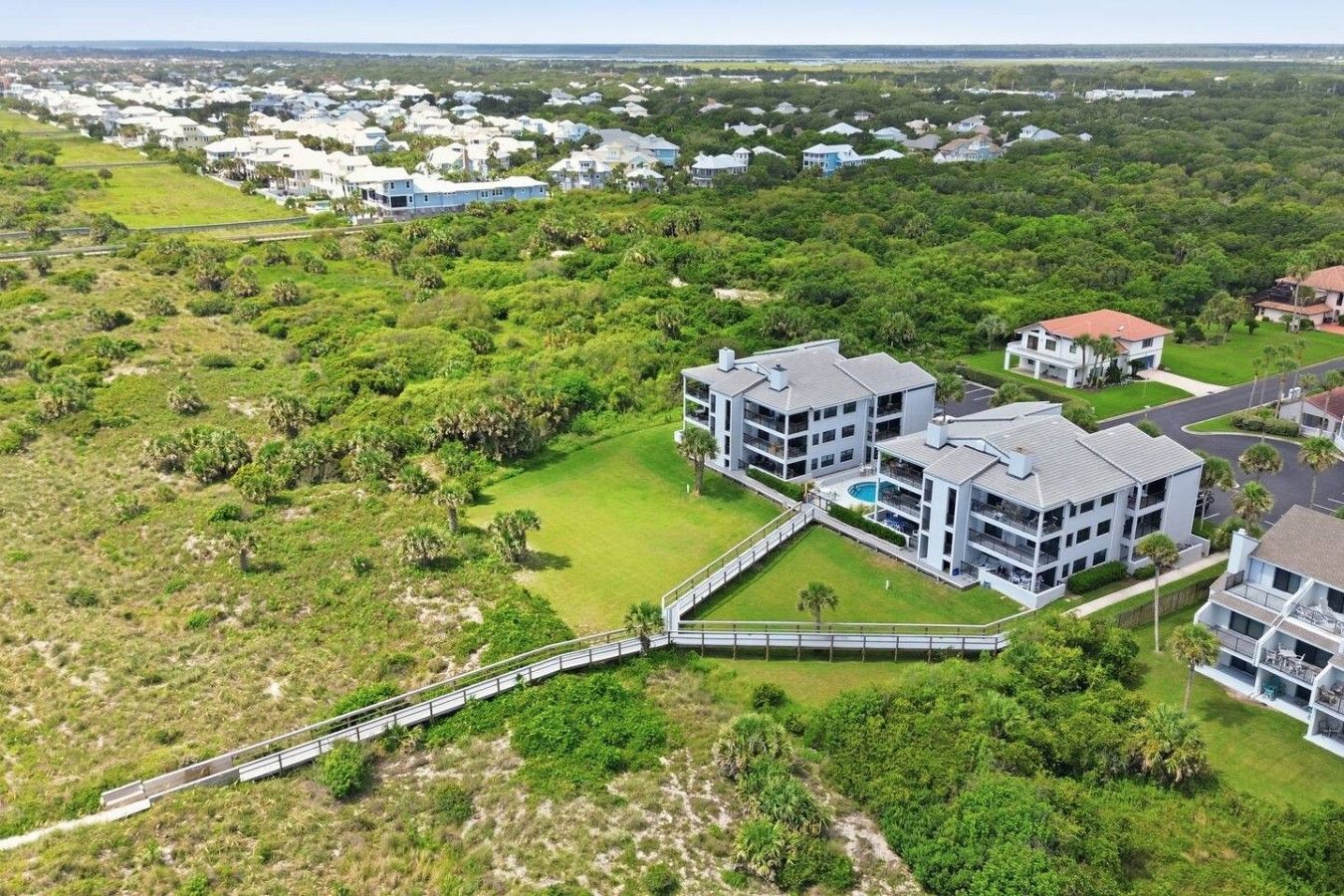 A residential area with modern multi-story buildings, a swimming pool, and a bridge connecting different sections.