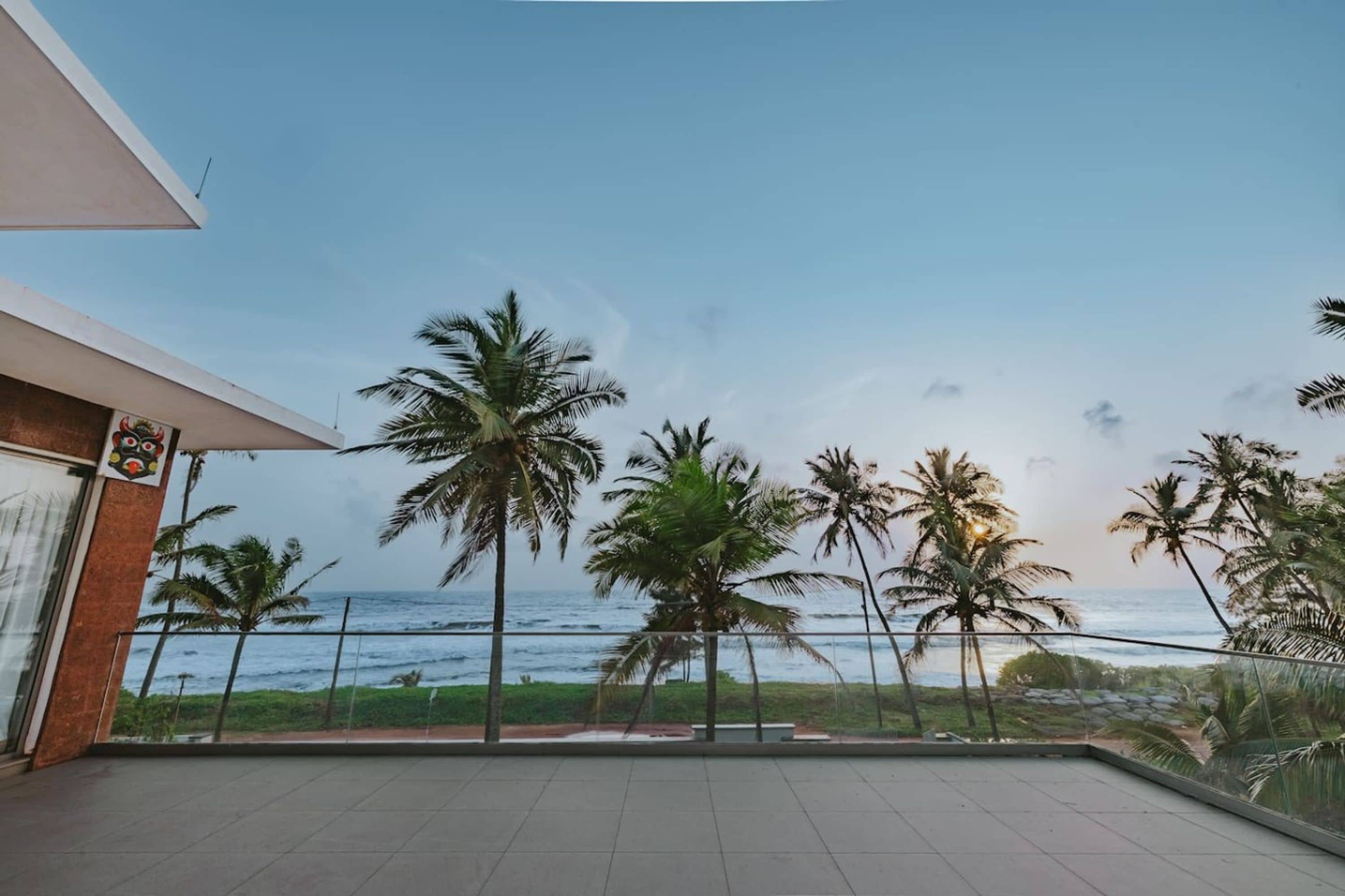 A balcony with a view of the ocean and palm trees.