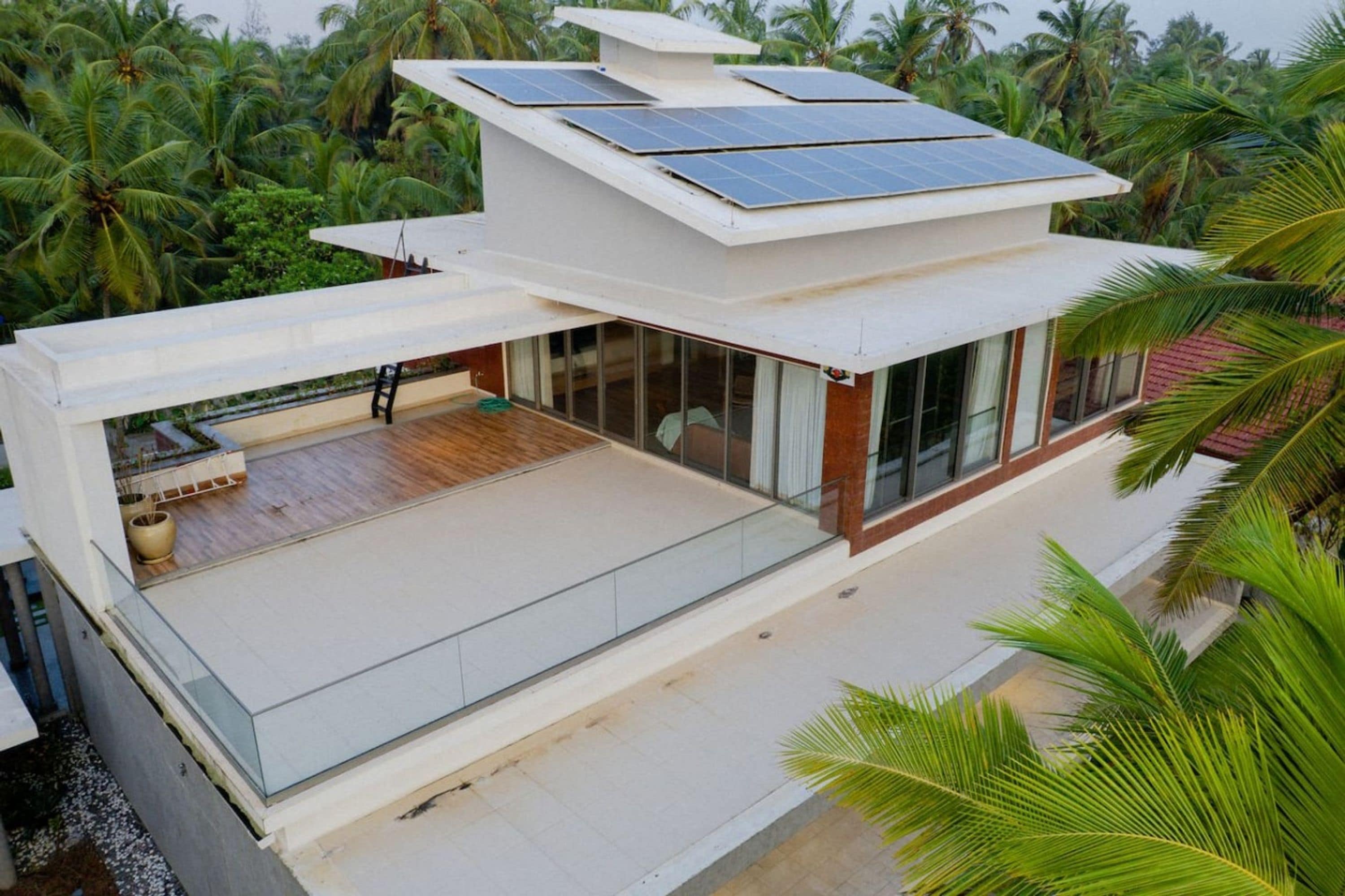 A modern house with a flat roof, large windows, and a balcony.