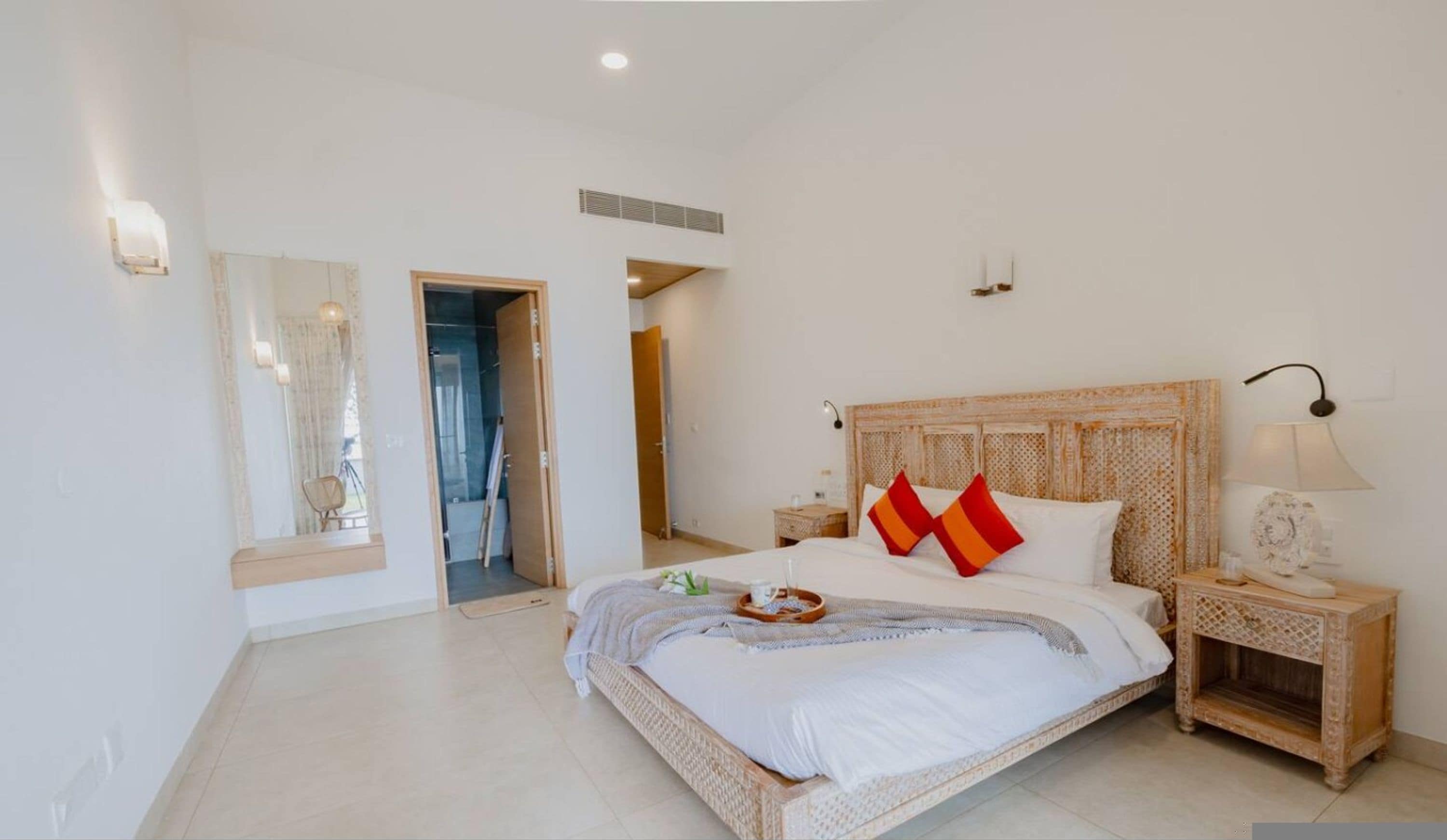 Un dormitorio espacioso con una cama grande, un cabecero de madera y una mesita de noche con una lámpara.