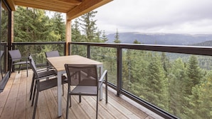 A wooden deck with a table and chairs, overlooking a forested landscape. - Superior Chalet # 27 With Sauna & Hot Tub (Stadl-Predlitz)