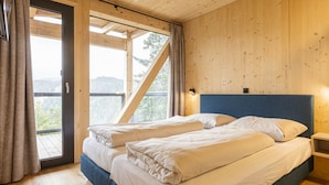 A bedroom with two beds, wooden walls, a balcony, and a view of the outdoors. - Superior Chalet # 27 With Sauna & Hot Tub (Stadl-Predlitz)