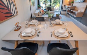 A dining table set with white plates, bowls, cutlery, and glasses, with a vase of flowers in the center. - Corporate Stays First del Sol - 301 (Asunción)