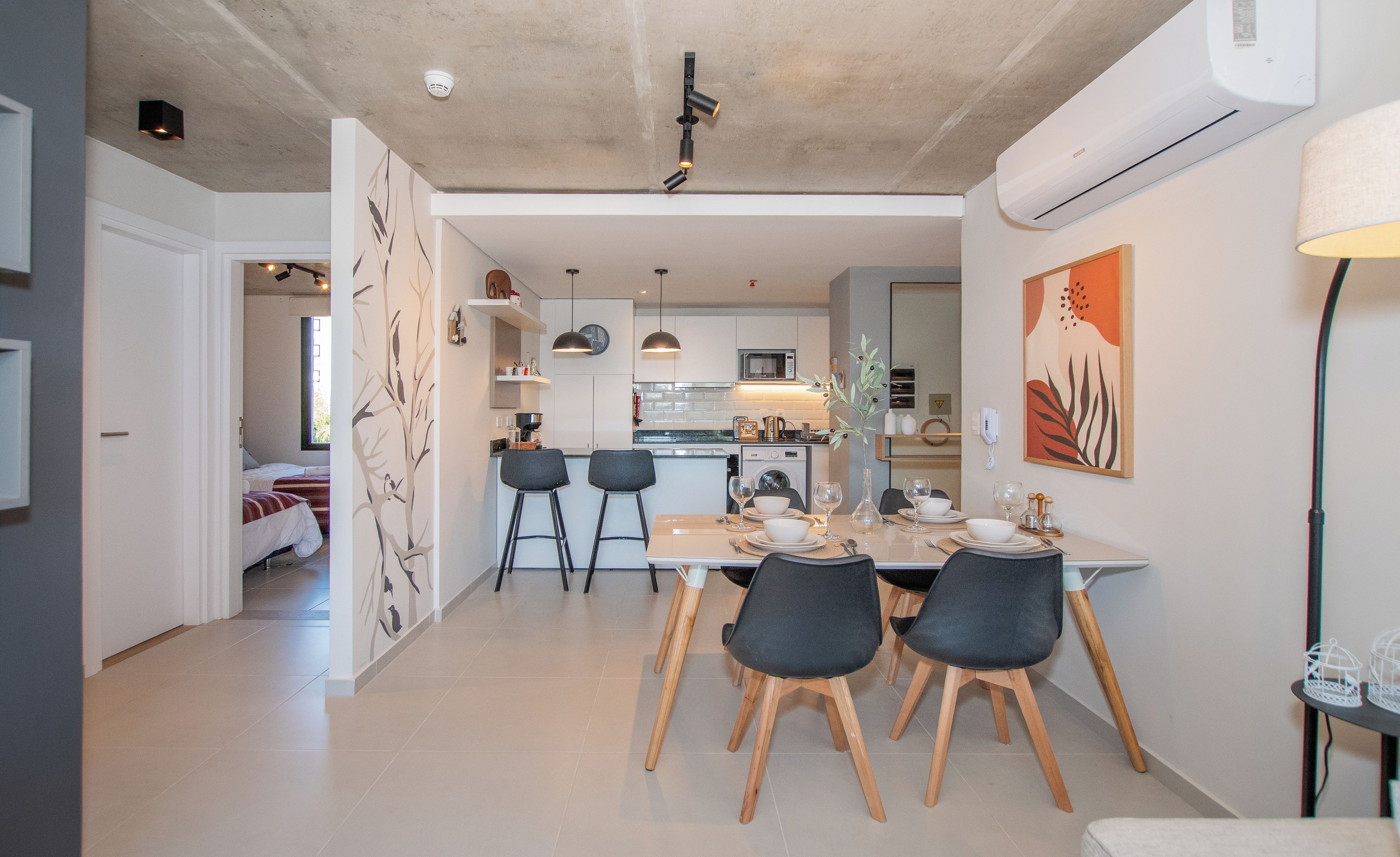 Cozinha moderna com micro-ondas, pia e área de refeições com cadeiras e uma mesa posta para uma refeição.