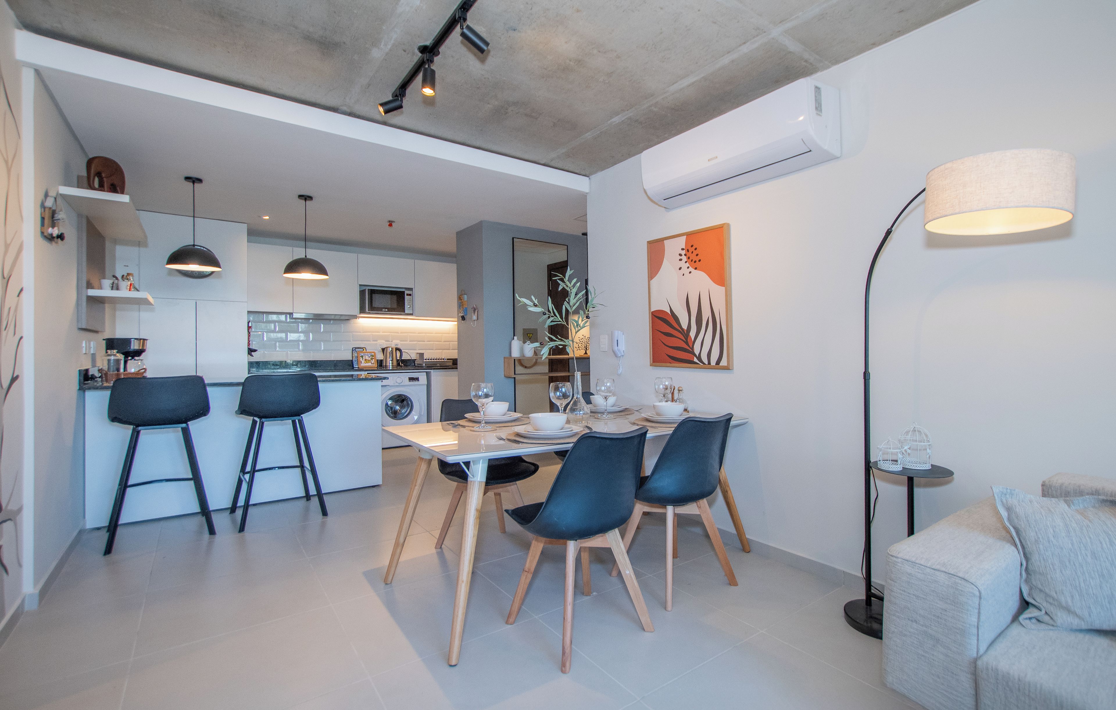 Una cocina moderna con comedor, taburetes de bar y una mesa dispuesta para dos.
