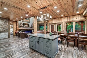 A spacious kitchen with a central island, wooden ceiling, and large windows. - Luxury4bdrmCabin-LgPool-HotTub-5MinParkway-Special (Sevierville)