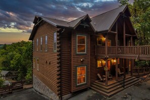 A two-story log cabin with a balcony, multiple windows, and a porch area. - Indoor Golf Cabin Amazing Views Arcade 8BRDM Cabin (Sevierville)