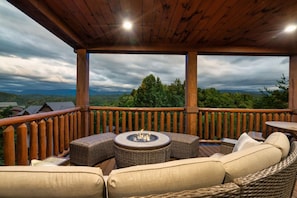 An outdoor deck with a fire pit, wicker furniture, and a view of the surrounding landscape. - Indoor Golf Cabin Amazing Views Arcade 8BRDM Cabin (Sevierville)
