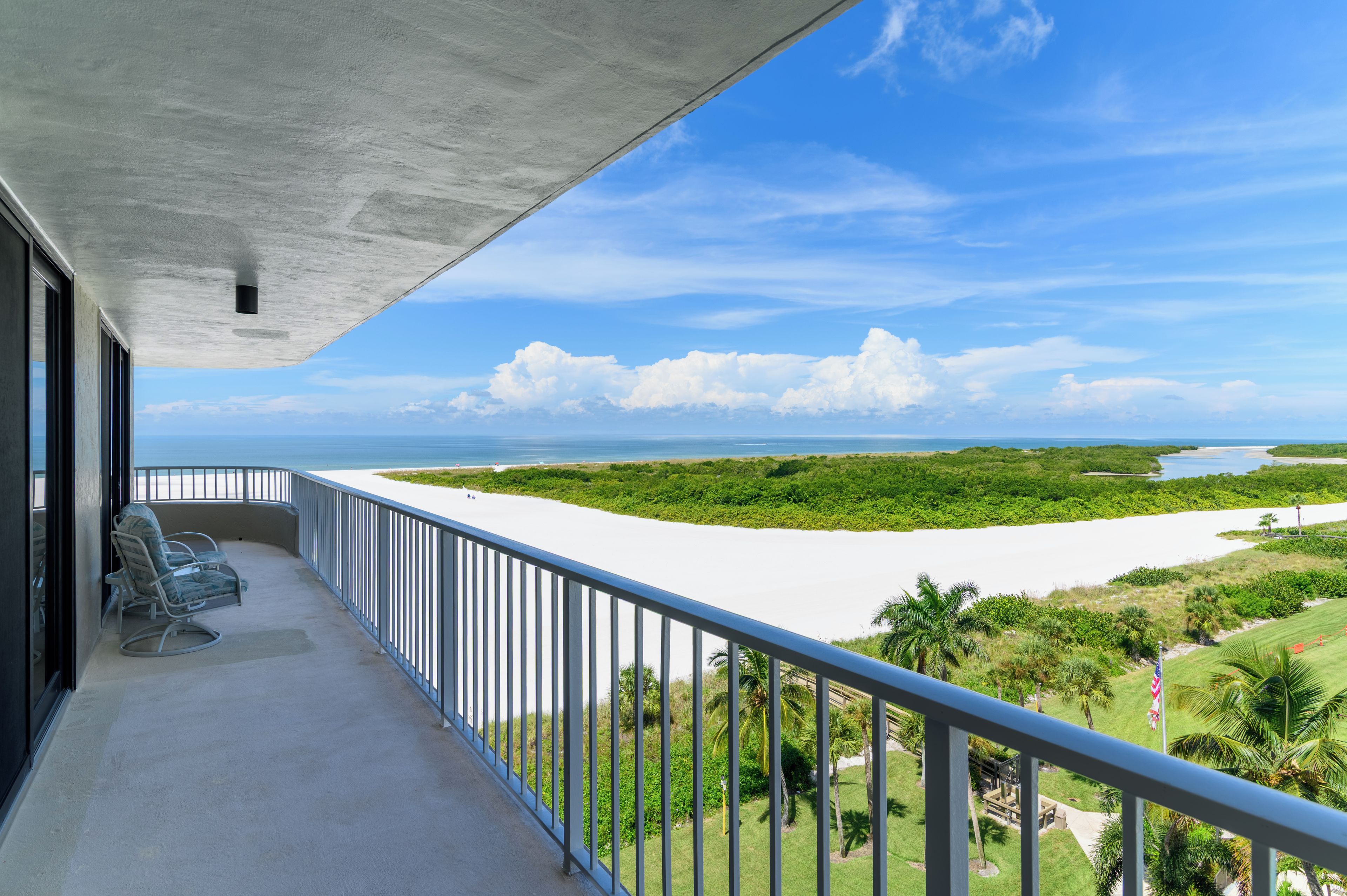 A balcony with a view of a beach and a river.