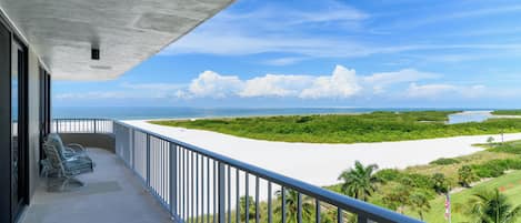 A balcony with a view of a beach and a river.